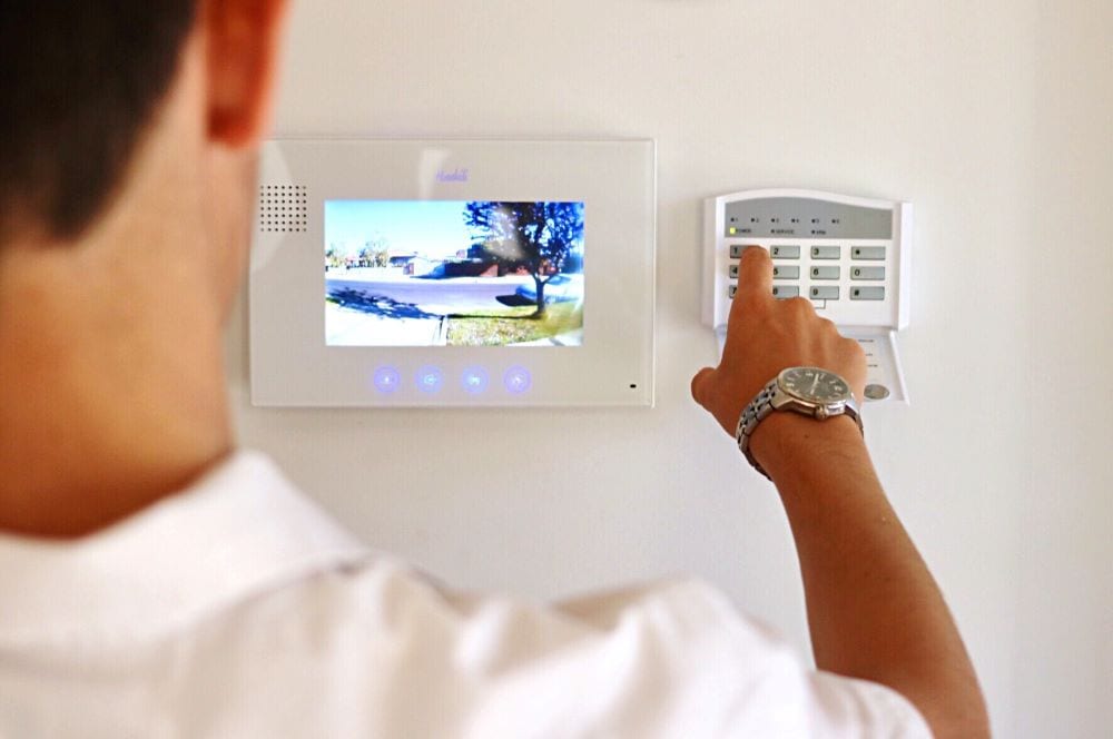 A man activating a button on a home security system.