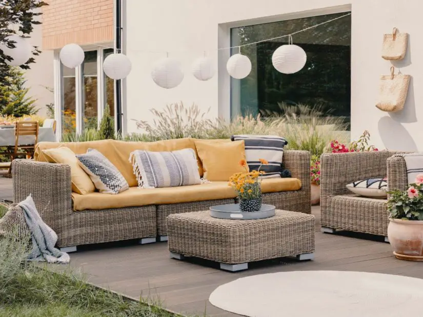 A patio with wicker furniture and yellow pillows.