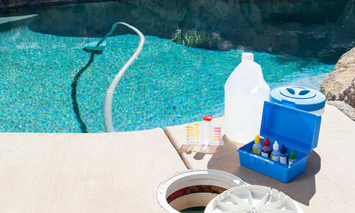 A swimming pool with a bottle of water next to it, showcasing pool tools.