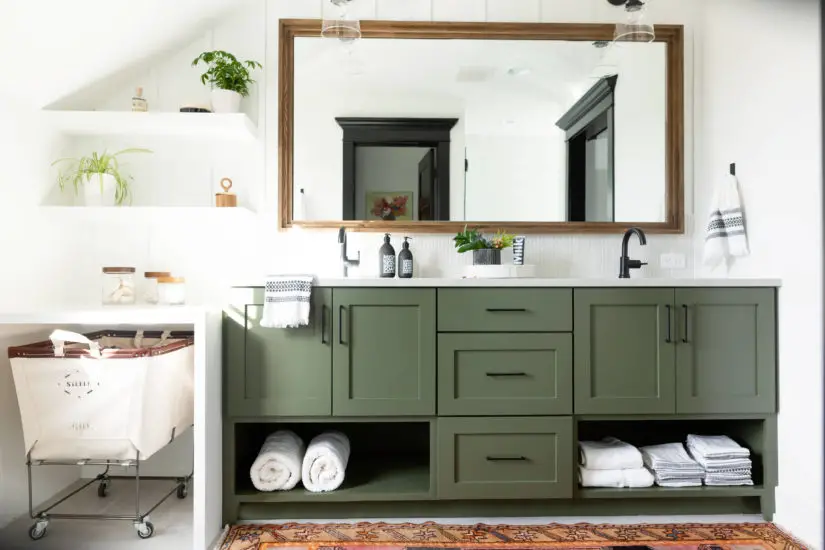 A bathroom with green cabinets and a rug.