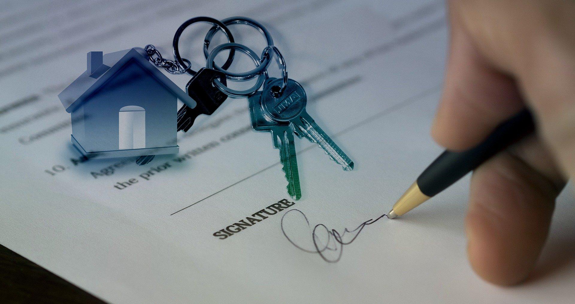 A person signing a document to sell their house.