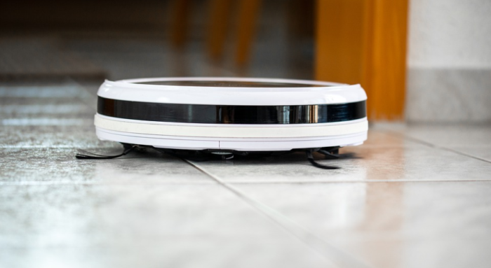 A smart robotic vacuum cleaner on the floor of a house.