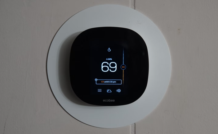 A smart thermostat is mounted on a wall in a smart home.