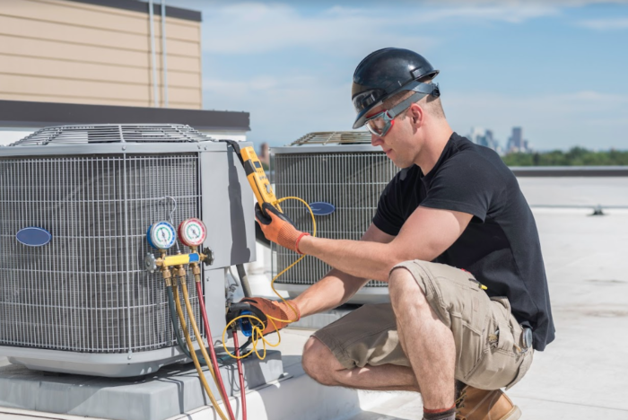 A man performing air conditioning maintenance on a roof.
