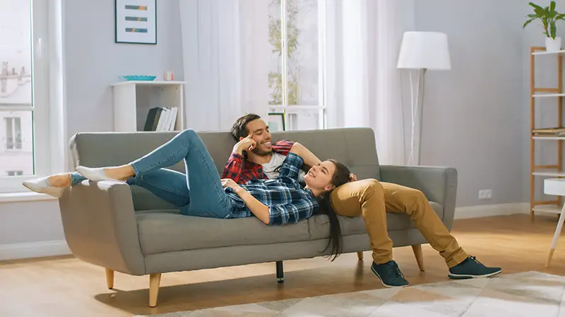 Two people sitting on a couch in a living room.