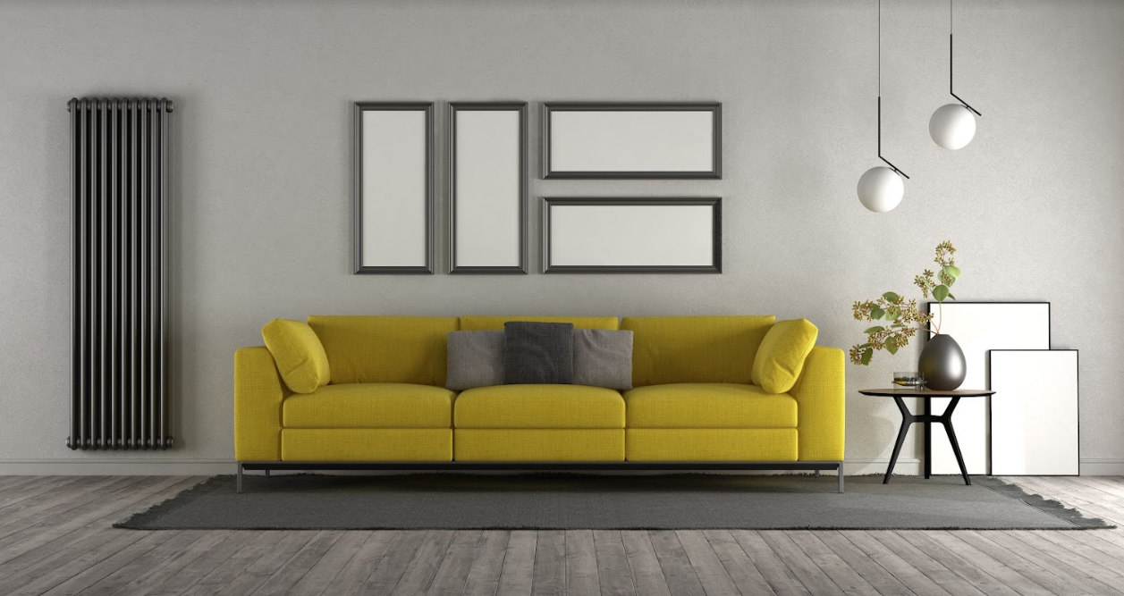 A yellow sofa in a room with framed pictures and hardwood flooring.