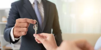 Man in suit handing house keys to another person