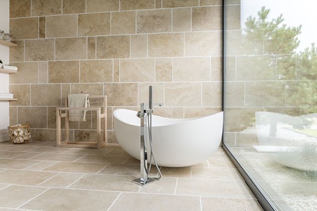 A bathroom with a marble bathtub and tiled walls.