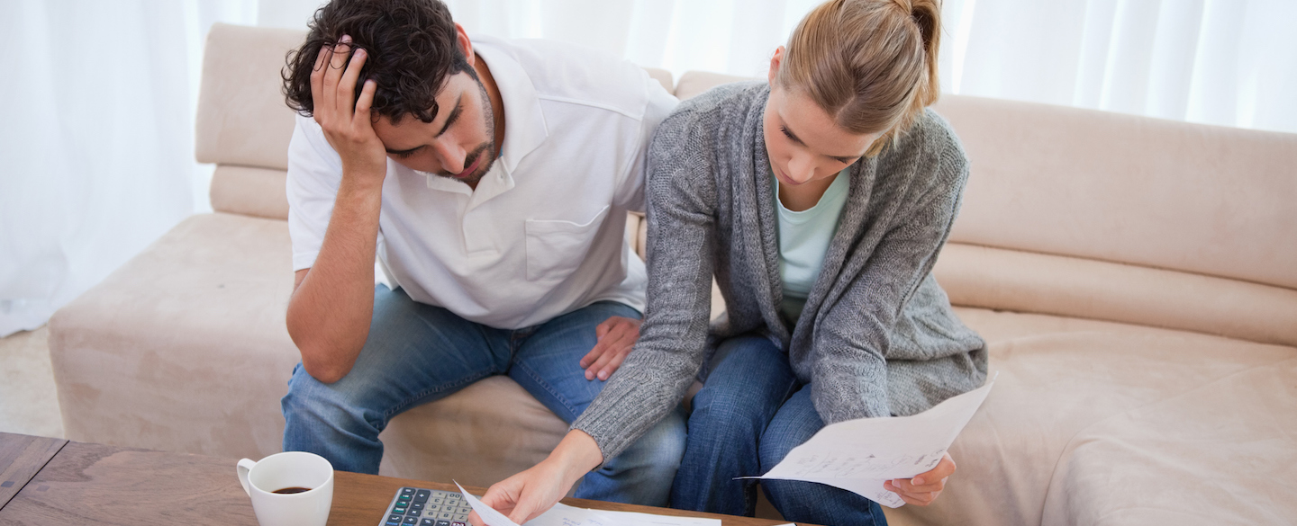 A man and woman sitting on a couch exploring mortgage relief programs while reviewing their finances.