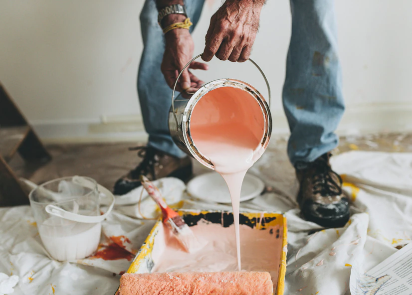 A man pouring interior paint into a bucket.