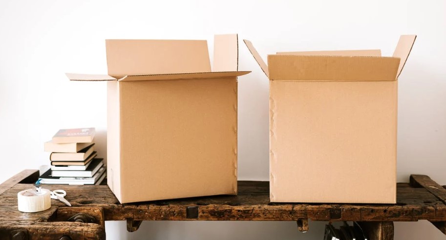 Two cardboard boxes sitting on a wooden table, ready to store large objects.