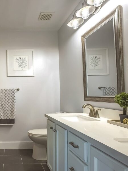 A bathroom with a white vanity, sink and mirror, equipped with bathroom fans.