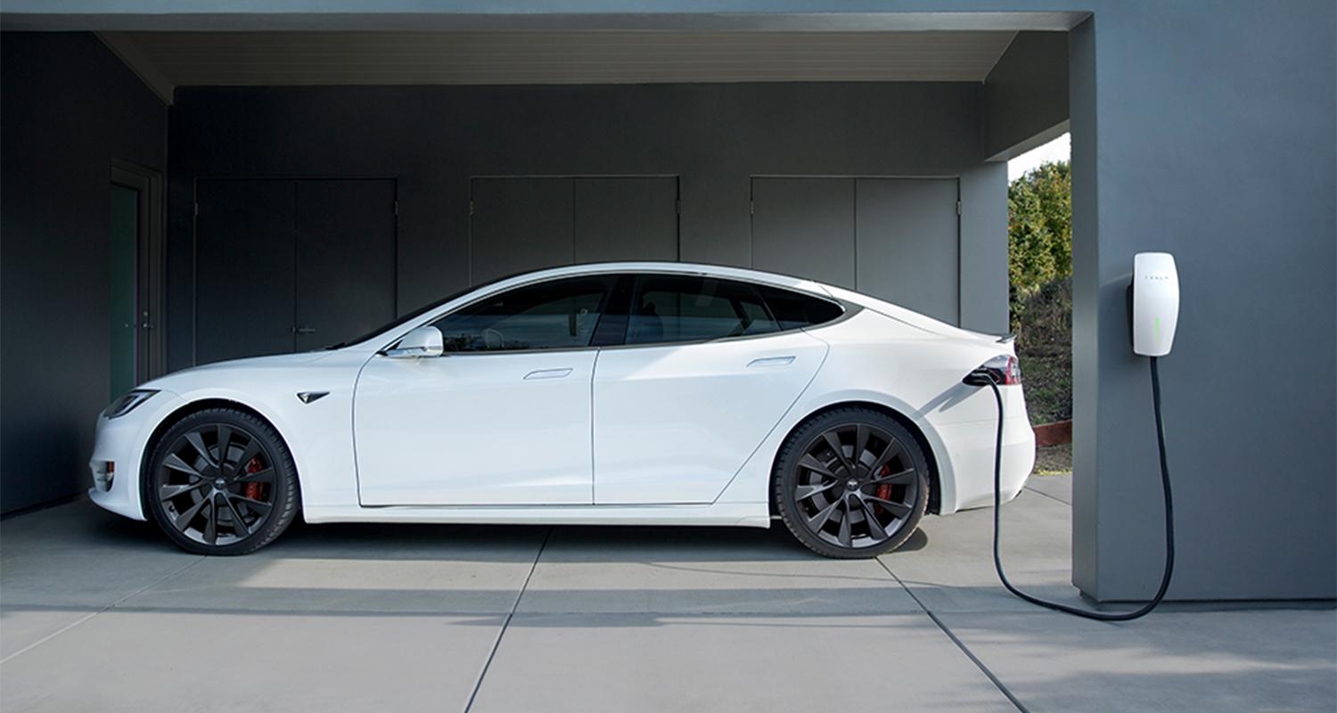 A white Tesla Model S parked in a home garage.