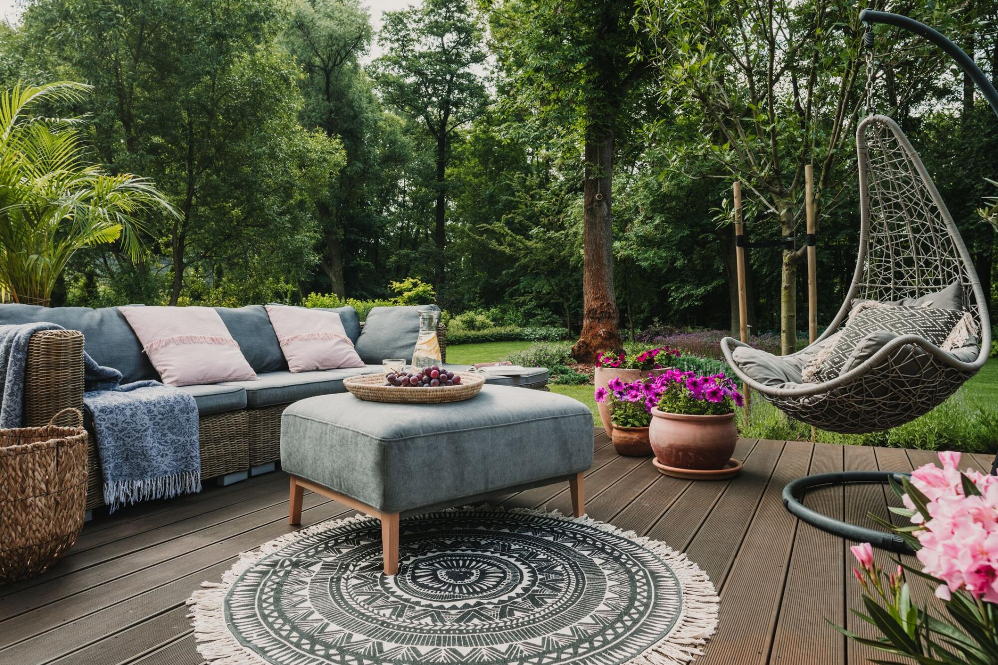 A wooden deck with a hanging sofa and a rug, perfect for a patio.