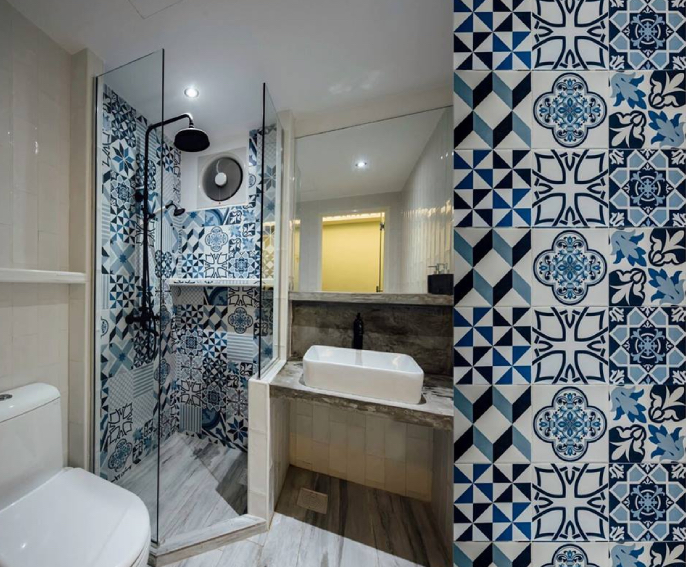 A bathroom with blue and white tiled walls featuring bathroom fans.