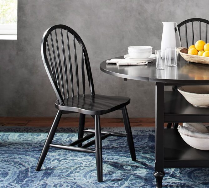A black dining room table and chairs with a timeless blue tablecloth.
