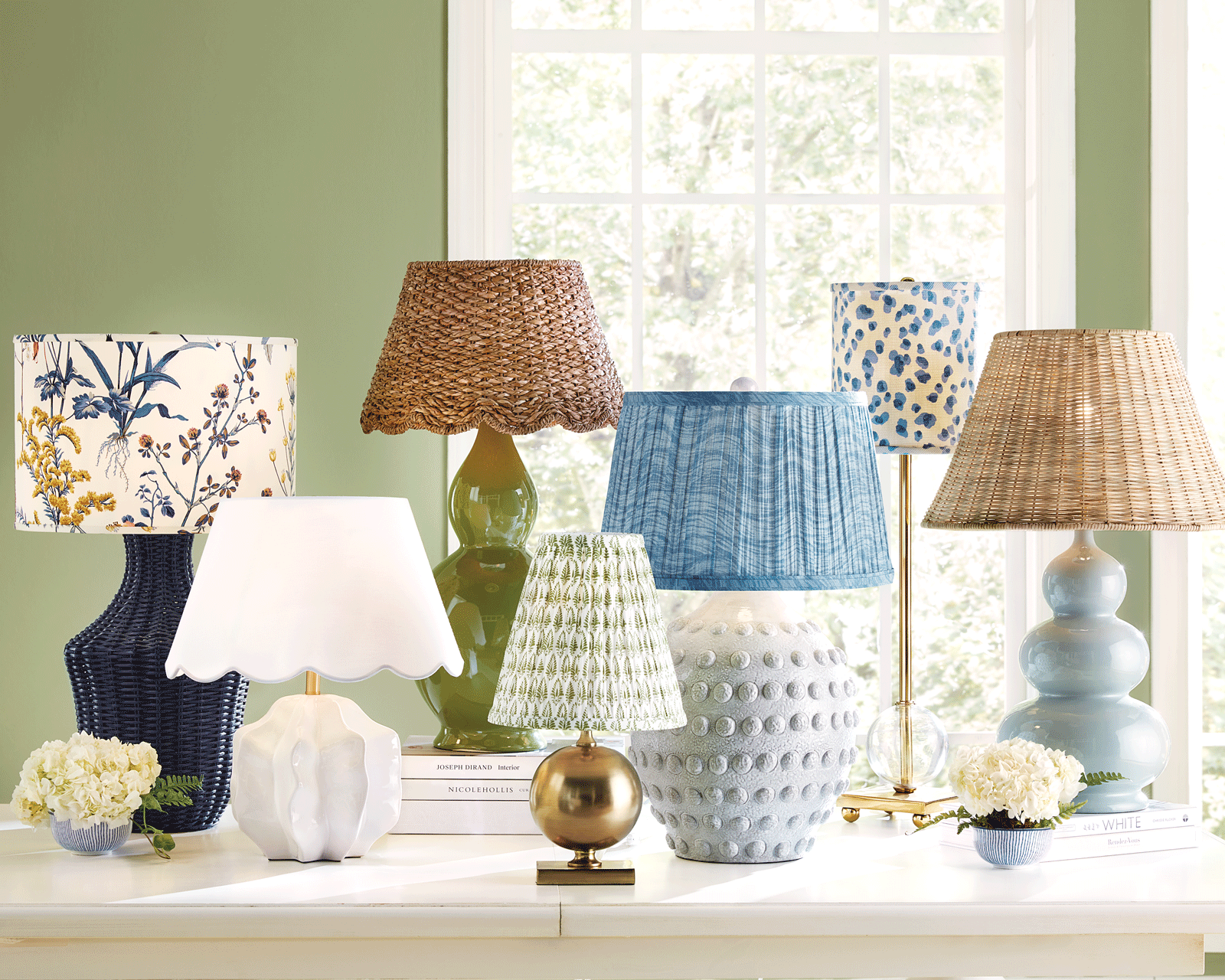 A group of lamps with unique fabric lampshades on a table in front of a green wall.