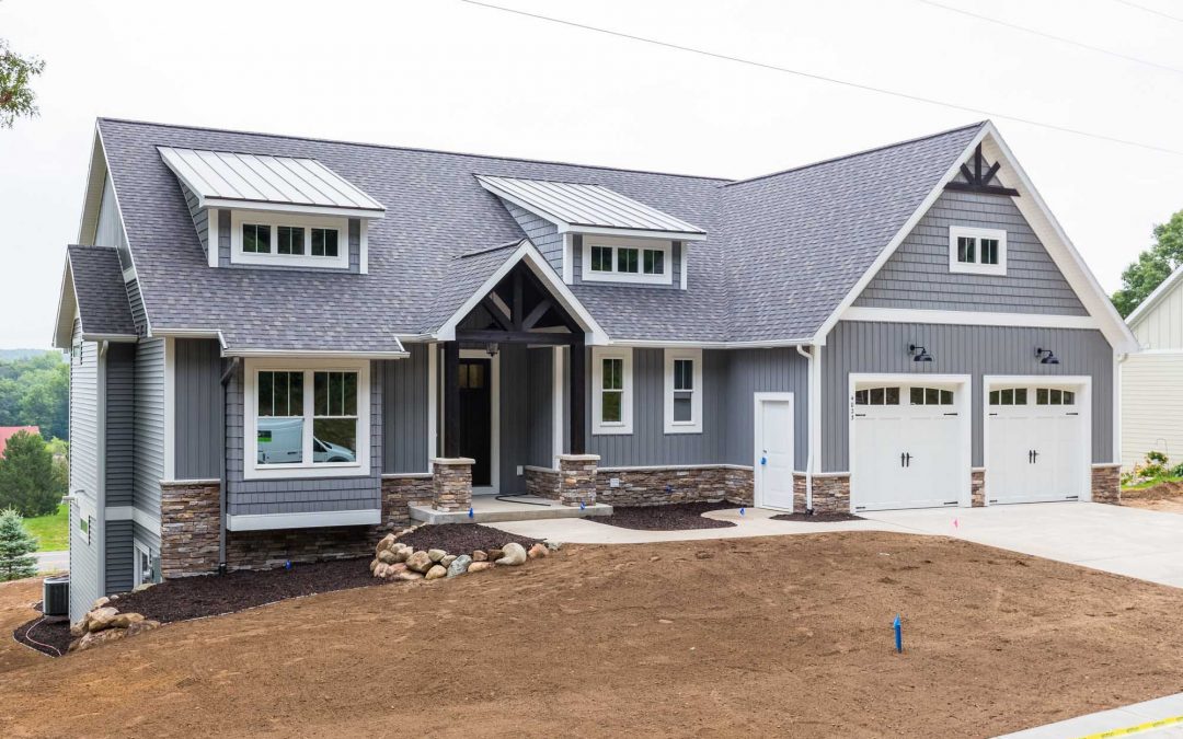 A custom-built home with gray siding and a garage.