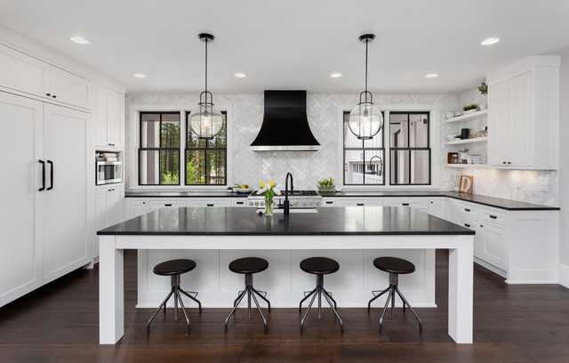A modern kitchen with black counter tops and stools.