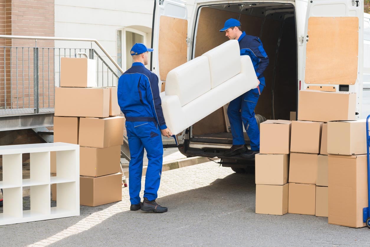 Two moving company workers loading furniture into a moving van.