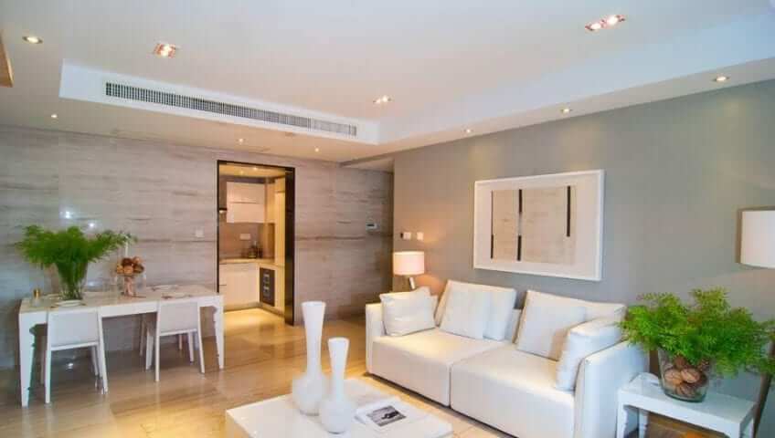 A living room with white furniture and ducted air conditioning.
