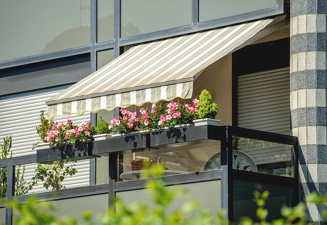 An awning designed to keep heat out, adorned with flowers on the balcony of a building.