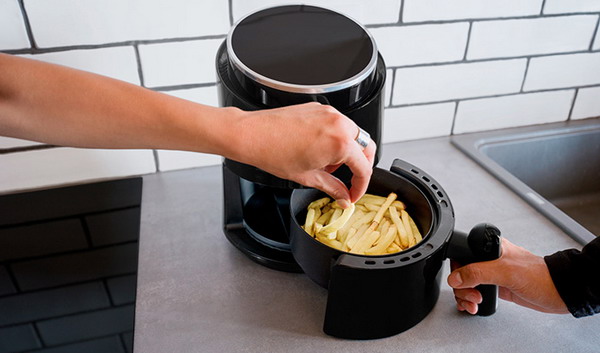 A person is using a kitchen appliance to fry food.