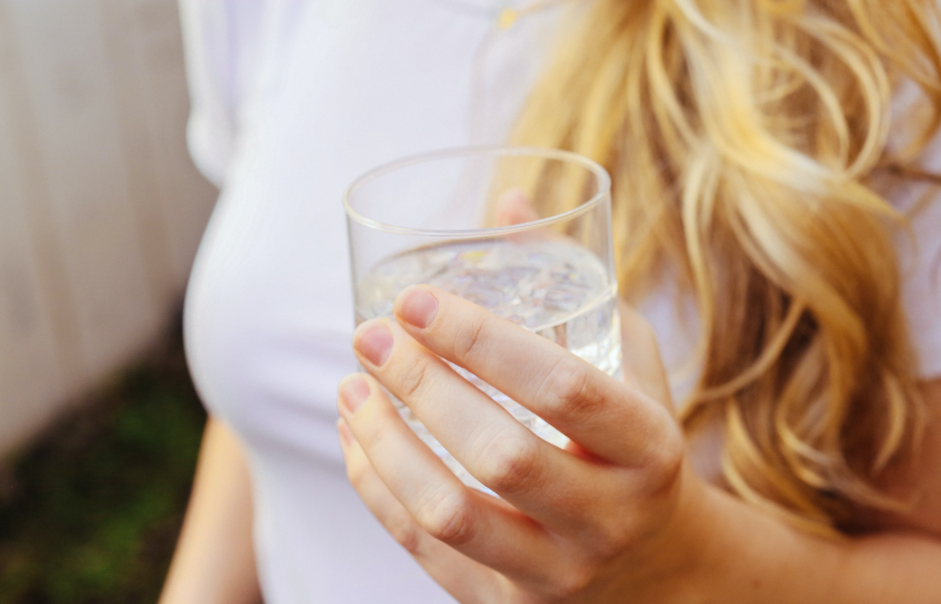 A woman holding a glass of water with freezer ice.