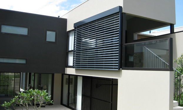 A modern house with black shutters and an outdoor balcony.