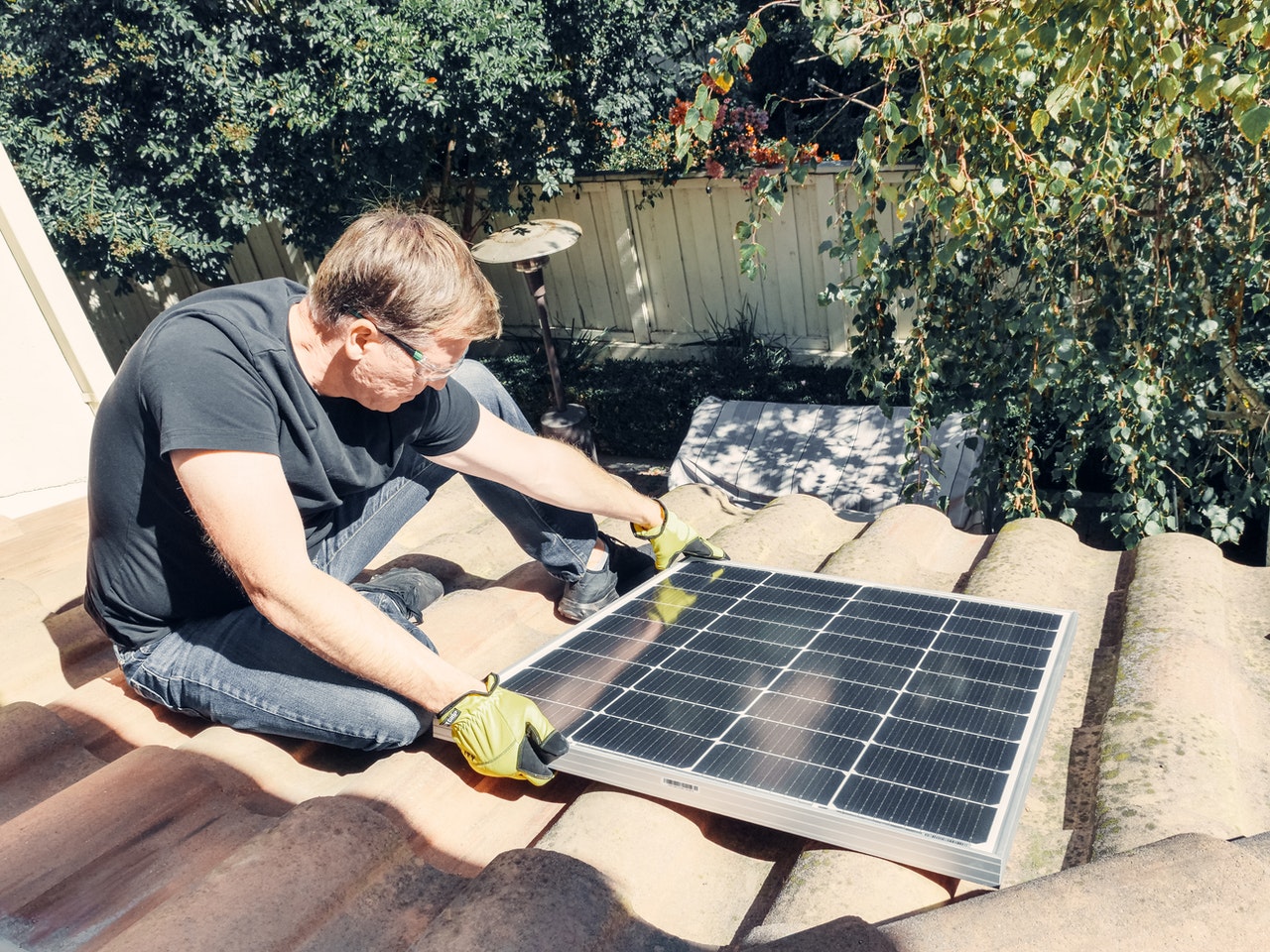 A man installing a sustainable solar panel on a property roof.