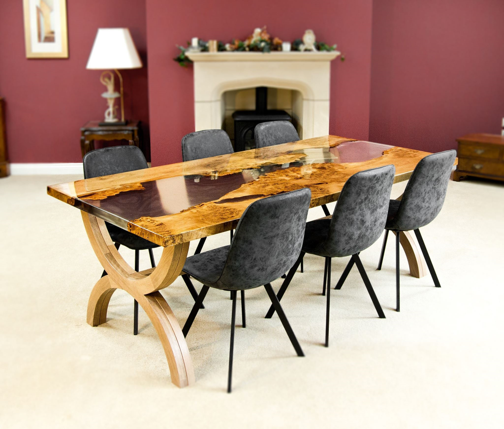 An epoxy dining table with six chairs and a fireplace.