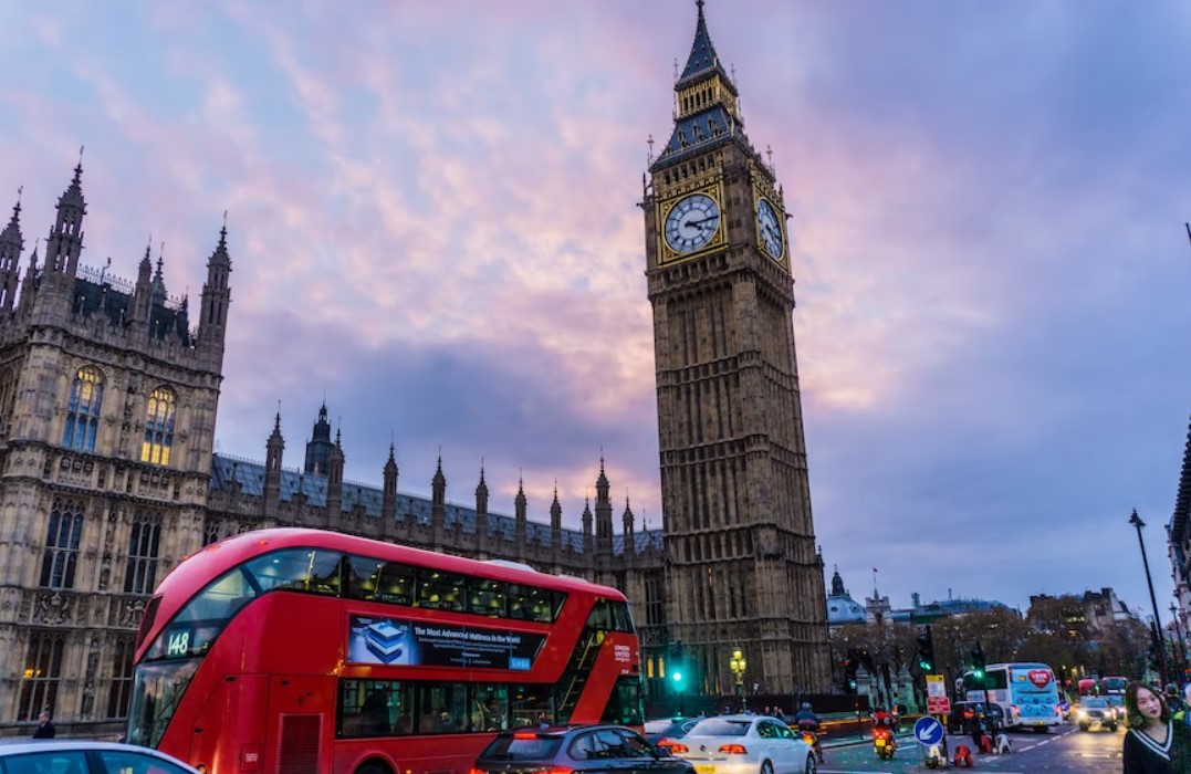 A red double decker bus drives past Big Ben in London, showcasing the vibrant city's good property.