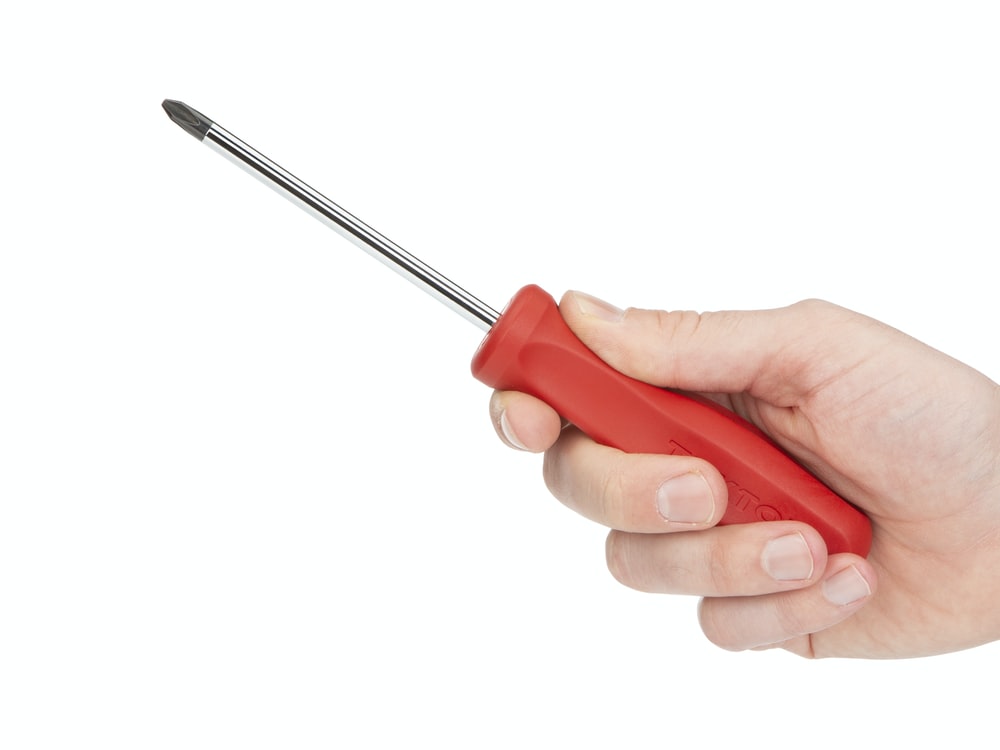 A person's hand holding a red screwdriver while doing Fall-Time Chores.