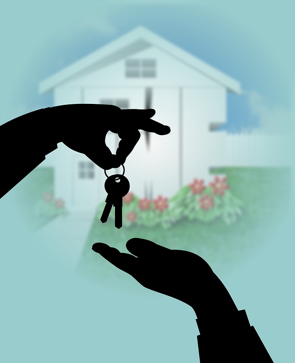 A person selling home gives a house key to another person.