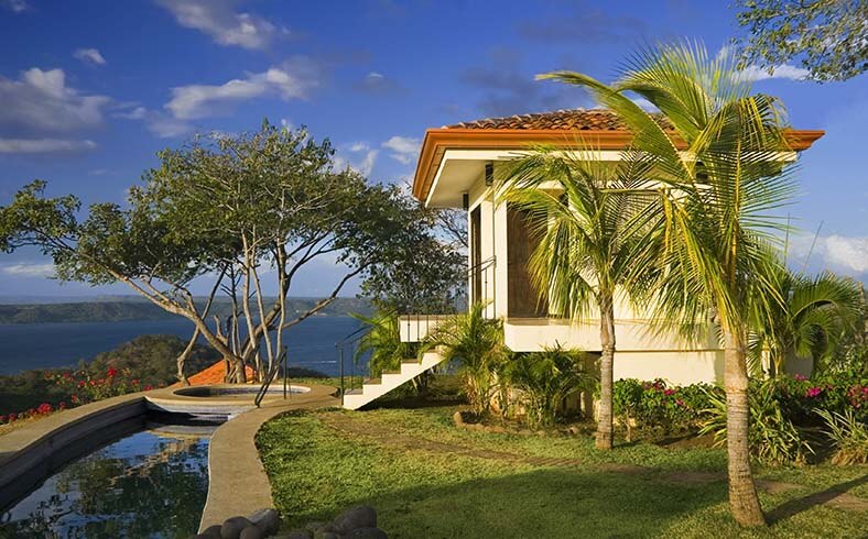 A tropical house with a pool and palm trees available for buying property abroad.