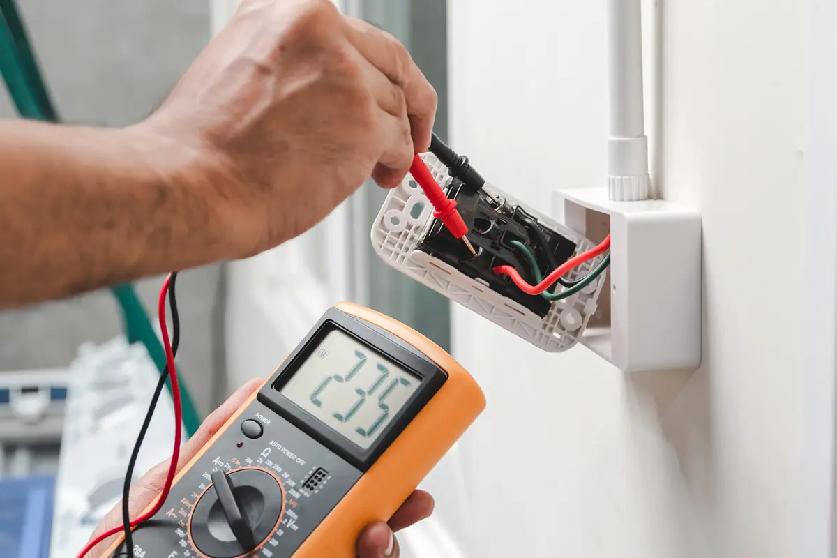 A Do I Need an Electrician? man using a multimeter to check the wiring of a house.