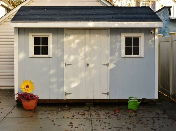 A blue shed with a flower pot in a backyard.
