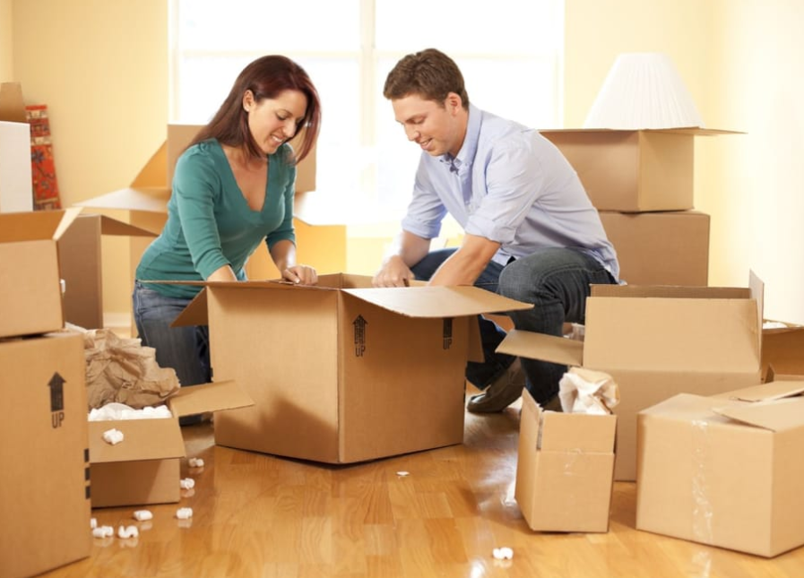 Trusted and professional NYC movers assisting a man and woman with moving boxes in a room.