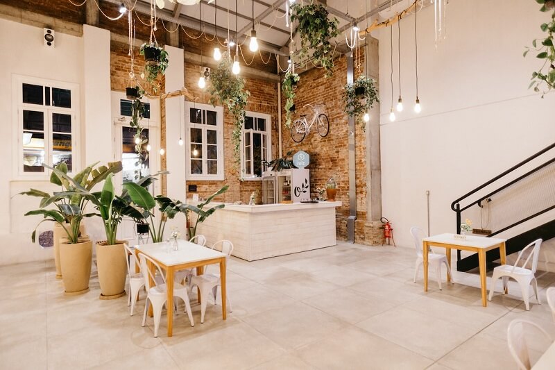 A coffee shop with modern white tables and chairs in a charming brick building.