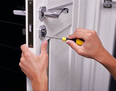 Emergency locksmith using a screwdriver to open a door.