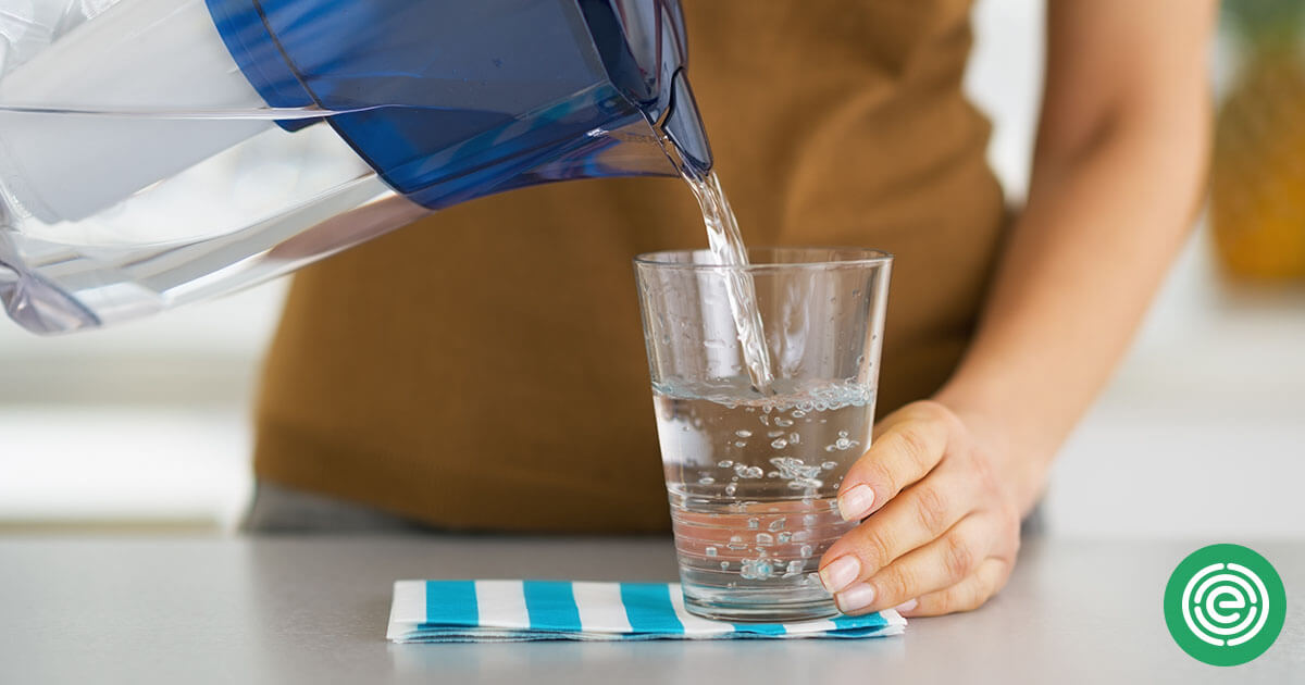 A woman safely pouring water into a glass.