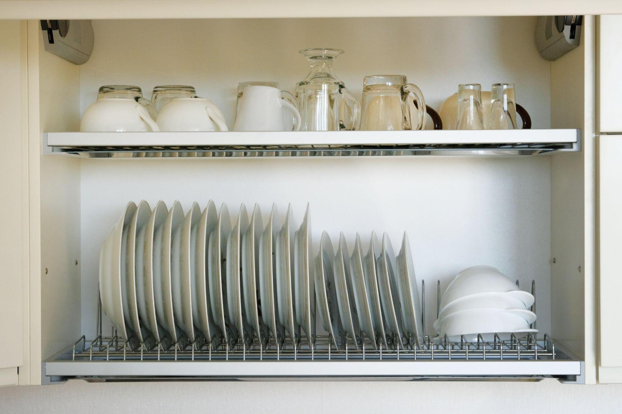 An organizational kitchen cabinet with a rack of dishes.