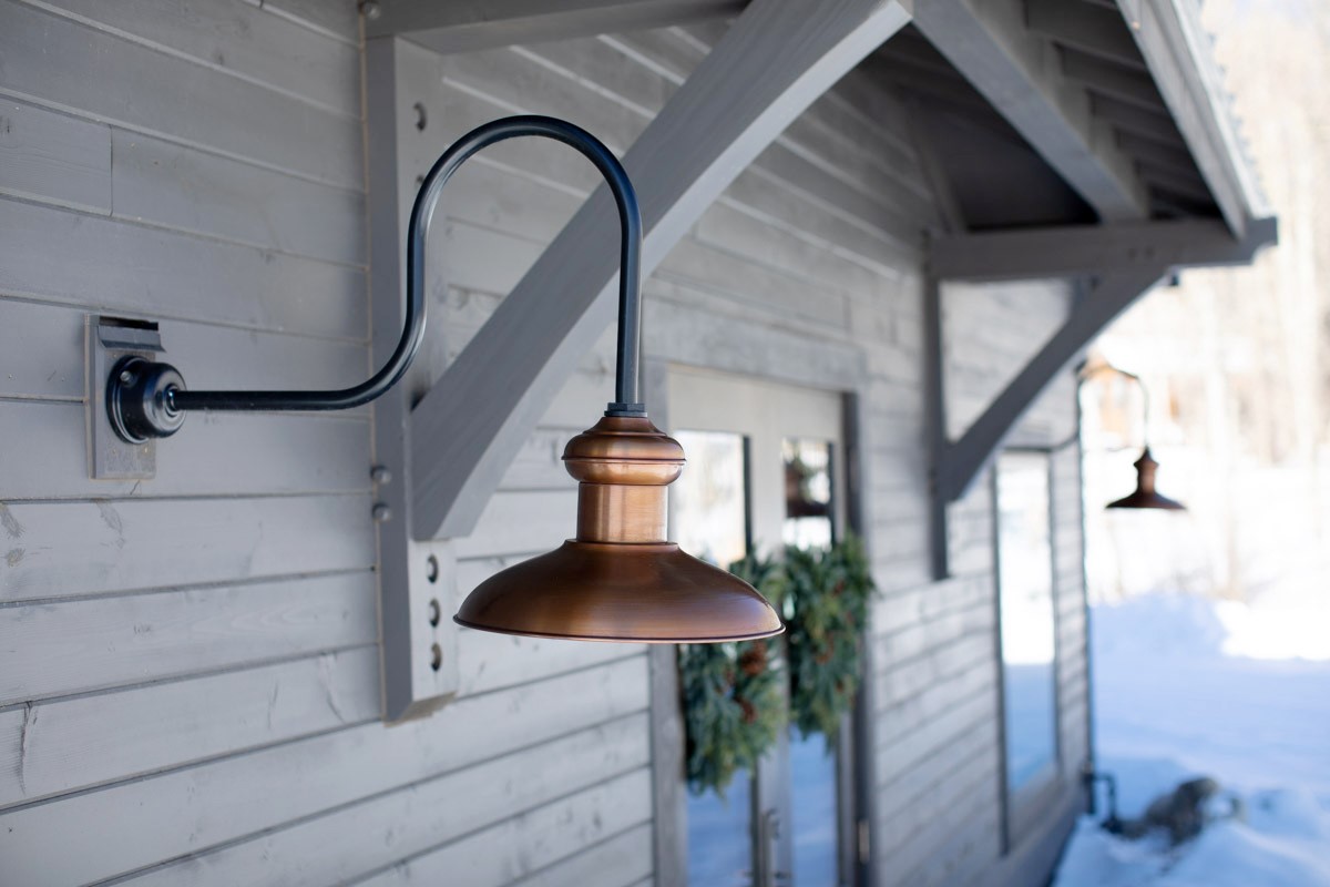 An outdoor copper lantern hanging on the side of a building.