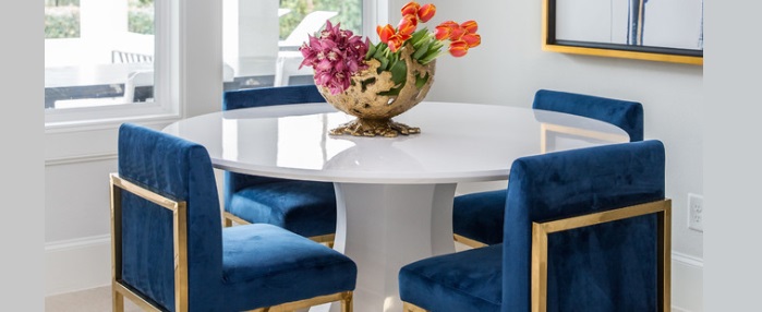 A dining room with blue velvet chairs and a gold table, showcasing what to put on the dining table.