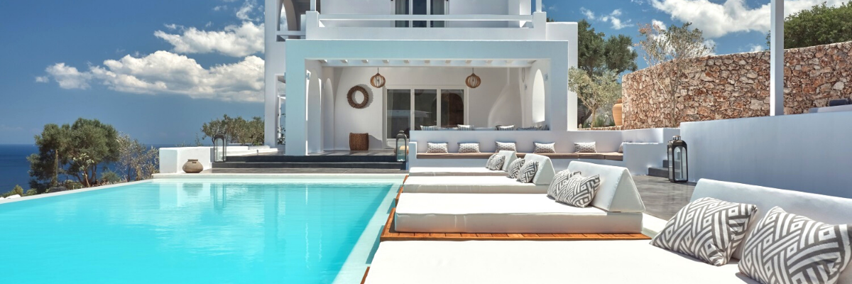A white house with a swimming pool and lounge chairs, perfect for family holidays.