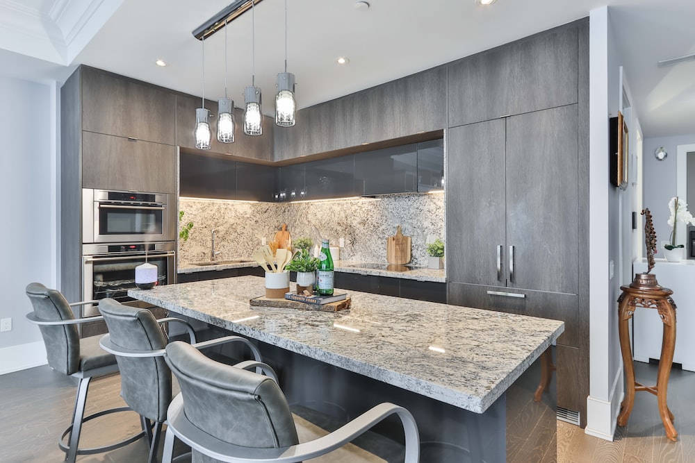 A modern kitchen with grey cabinets and marble counter tops managed by Property Management company.