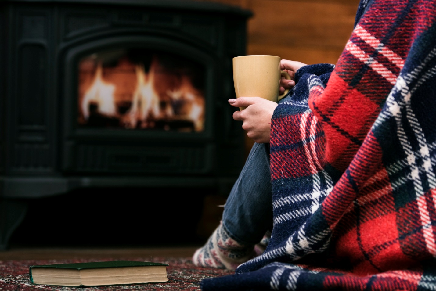 A woman is sitting by a fireplace enjoying a cup of coffee in Mississauga during winter.
