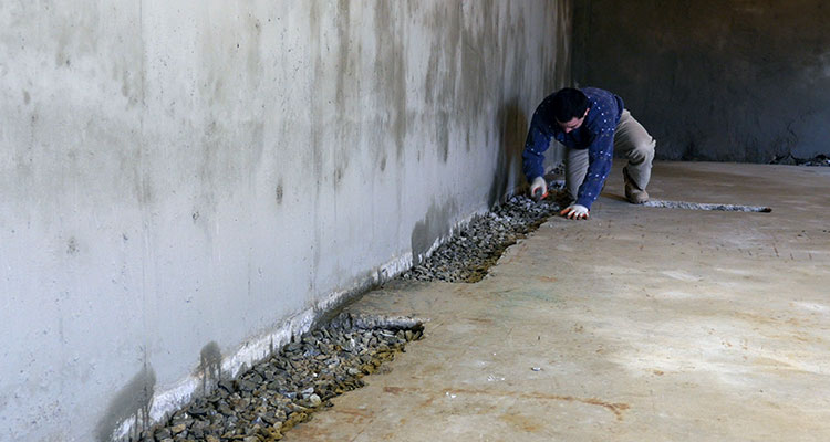 A man waterproofing a basement floor.