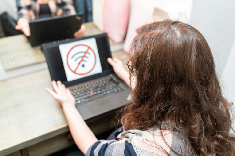 A woman is using a laptop with an internet shuts down sign on it.