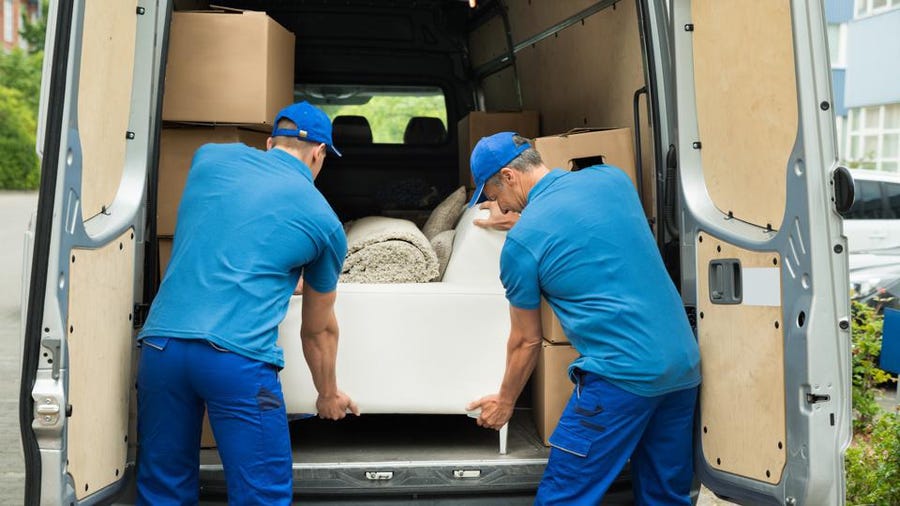 Two men from a moving company loading furniture into a moving van.